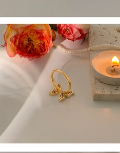 Close-up of golden butterfly ring with micro-set black stones on a romantic background