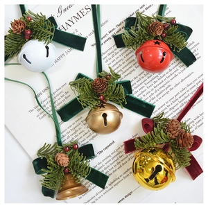 Detailed view of assorted Christmas bell ornaments with velvet bows and pine cones