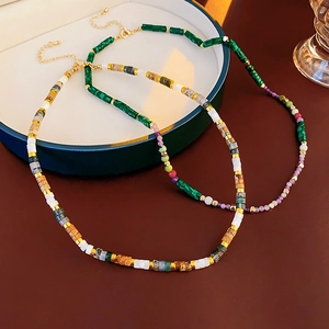 Detail of beaded necklaces with green stone and multicolor beads with gold accents