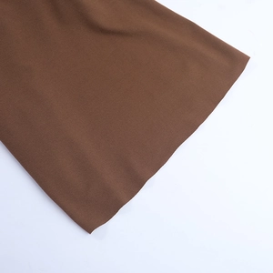 Gros plan détaillé montrant la texture fine et le tissage du tissu marron de la robe