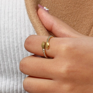 Detailed view of adjustable gold hugging hands ring with zircon stone on model