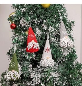 Detailed view of knitted Christmas gnome ornaments with snowflake embroidery on a tree