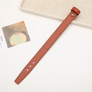 Brown leather wrist strap detail with metal rivet fastener and adjustment holes
