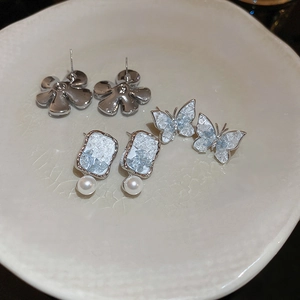 Detailed set of silver flower and butterfly stud earrings with pearl and ice crystal texture