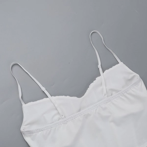 Close-up of white lace camisole adjustable straps and neckline detail on soft fabric