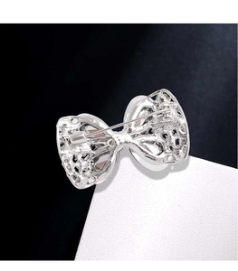 Detail view of the silver bow brooch back showing the secure metal safety pin closure