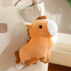 Close-up of cute plush pony keychain in orange brown hanging on a corduroy bag
