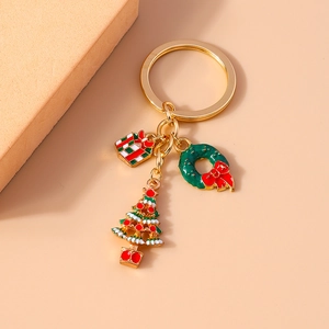 Close-up of golden Christmas keychain with enamel gift box, wreath, and tree charms
