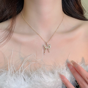Close-up of golden necklace with green gemstone and clear zircon butterfly pendant on model