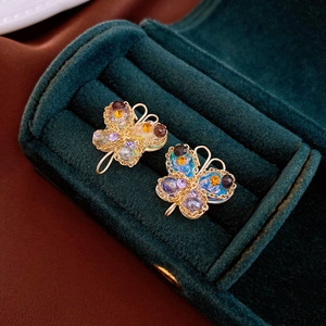 Macro shot of butterfly earring with colorful crystals in a dark velvet gift box