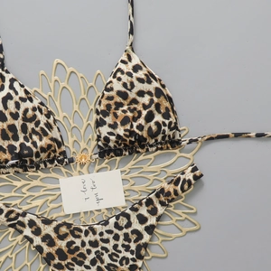 Detail of leopard print bikini with golden sun-shaped metal buckle on grey background