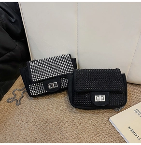 Close-up of black rhinestone chain bags with silver metal turn-lock on textured surface