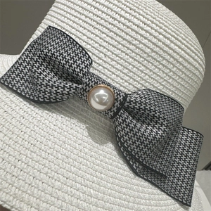 Close-up of houndstooth bow and pearl button on white straw bucket sun hat for women