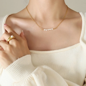 Ensemble collier en perles baroques et bague dorée porté par un mannequin avec style