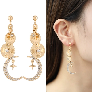 Gold celestial drop earrings with starburst pendants and rhinestones on model and white background