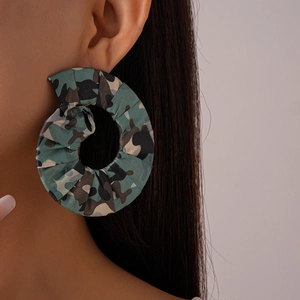Gros plan sur des boucles d'oreilles rondes en tissu avec motif camouflage sur mannequin