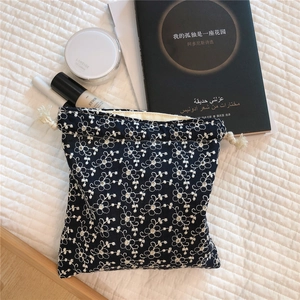 Detailed embroidery of white flowers on a navy cotton drawstring pouch with lifestyle items