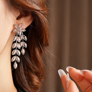 Close-up of silver flower and leaf tassel earrings with sparkling crystals on model