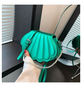 Detailansicht einer grünen Muschelhandtasche mit Perlenkette und vertikaler Texturierung