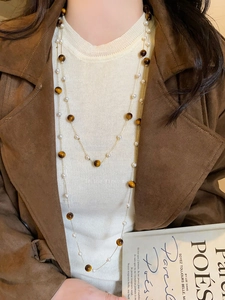 Close-up of double-layer tiger eye stone beads and white pearl necklace on model