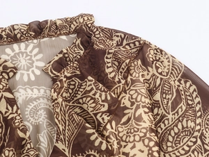 Detail van de ruffelkraag en paisleyprint op een transparante chiffon stof