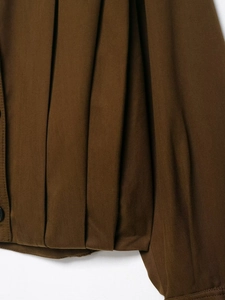 Detailed close-up of dark brown pleated fabric texture and twill cotton material