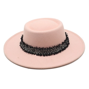 Detalle de sombrero de lana rosa con elegante cinta de flecos en tweed blanco y negro
