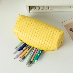 Detail of a bright yellow quilted pencil case with colorful pens on a desk