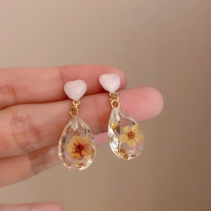 Dettaglio di orecchini fatti a mano in resina con fiori e perni a cuore rosa dolce