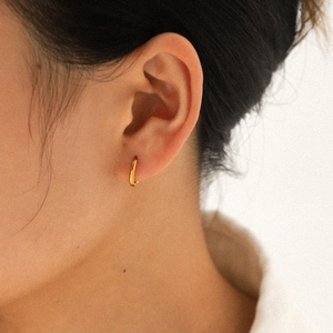 Gros plan d'une boucle d'oreille créole minimaliste en acier inoxydable doré 18 carats