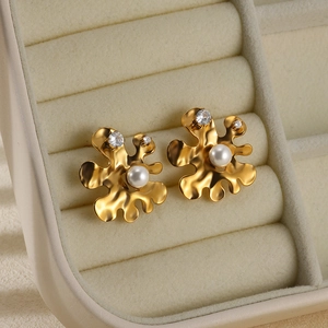 Macro shot of gold-plated stainless steel earrings with white pearls and heart zircons