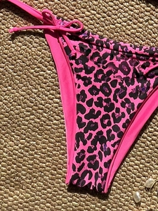 Close-up of pink bikini bottom with leopard print side panels and adjustable side ties