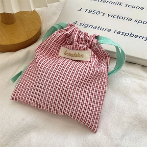 Detail of red and white checkered fabric drawstring bag with mint green cord accents