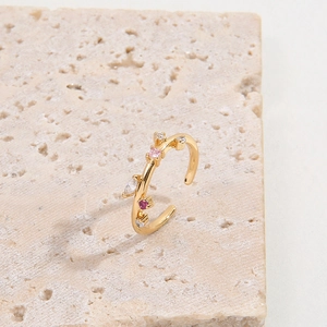 Minimalist adjustable gold ring featuring vibrant colorful zircon stones on stone background