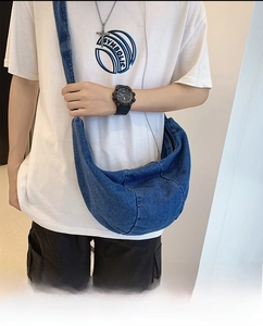 Detailed view of the large capacity blue denim crescent bag with a natural drape texture