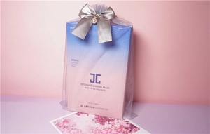 Close-up of facial mask sample in a transparent organza gift bag with a pearl bow