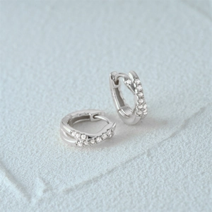 Macro shot of silver cross-over hoop earrings with sparkling pavé zircons detailing
