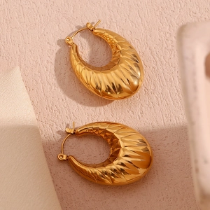 Detail of gold hollow oval earrings with geometric diamond pattern and metallic texture