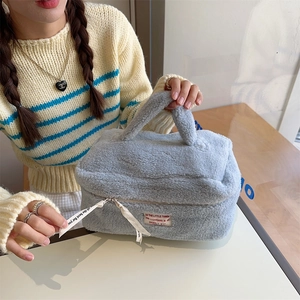 Close-up of a large light blue plush vanity case with elegant ribbon zipper details