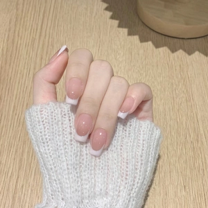 Detailed view of nude pink French tip press-on nails on a natural wooden background