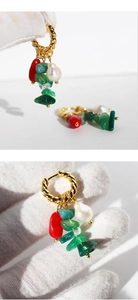 Macro shot of gold-plated twisted hoop earring with green stones and pearl tassel
