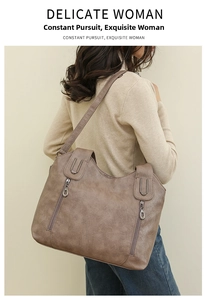 Detail of taupe vintage leather tote bag showing vertical zippers and metal U-ring