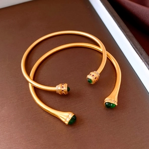 Detail of vintage gold-tone zircon open bangle with green gemstones and matte finish