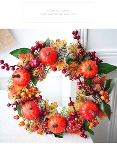 Detail of Halloween autumn wreath with pumpkins, red berries and acorns on white wall