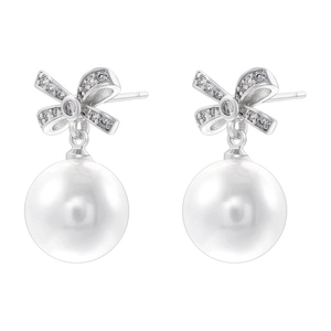 Macro shot of silver bow earrings featuring sparkling stones and a large white pearl drop