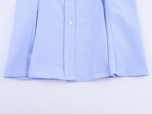 Dettaglio dell'orlo con bottone bianco su una camicia a maniche lunghe a righe blu