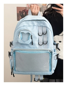 Detail of light blue nylon backpack featuring a heart-shaped clear pocket and mesh layer