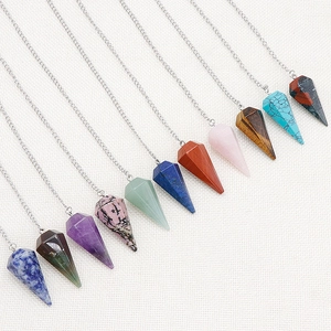 Multiple colors of hexagonal natural crystal stone pendulum necklaces on white fabric