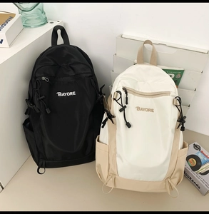 Close-up of black and khaki nylon backpacks with BAYORE logo in a modern studio setting