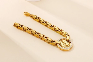 Detail of gold Cuban chain bracelet with CZ-encrusted boy and girl silhouette pendant